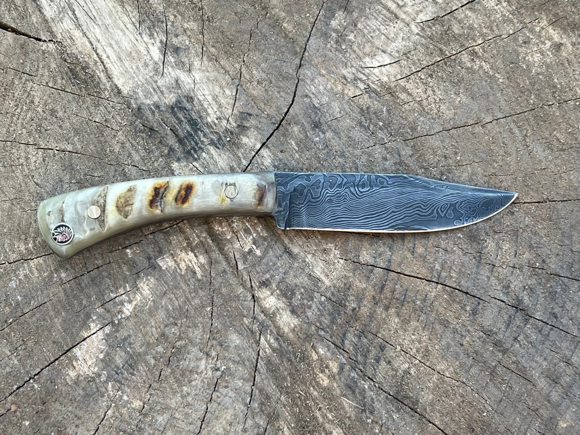 Hand-forged Damascus hunting knife on a stump