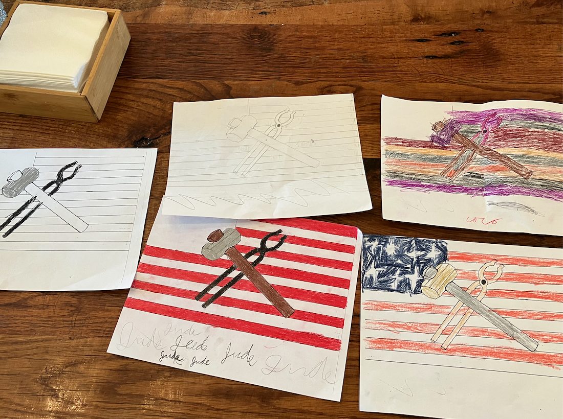 Hammer and tongs drawn over American flags